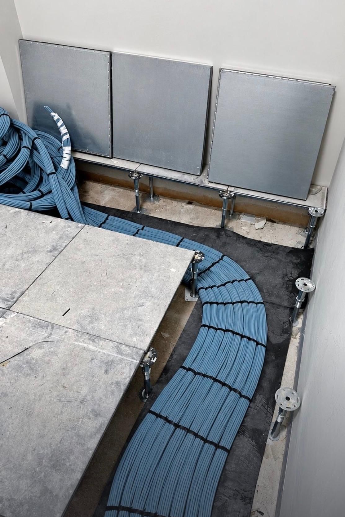 Curved run of blue cable looms under a raised floor