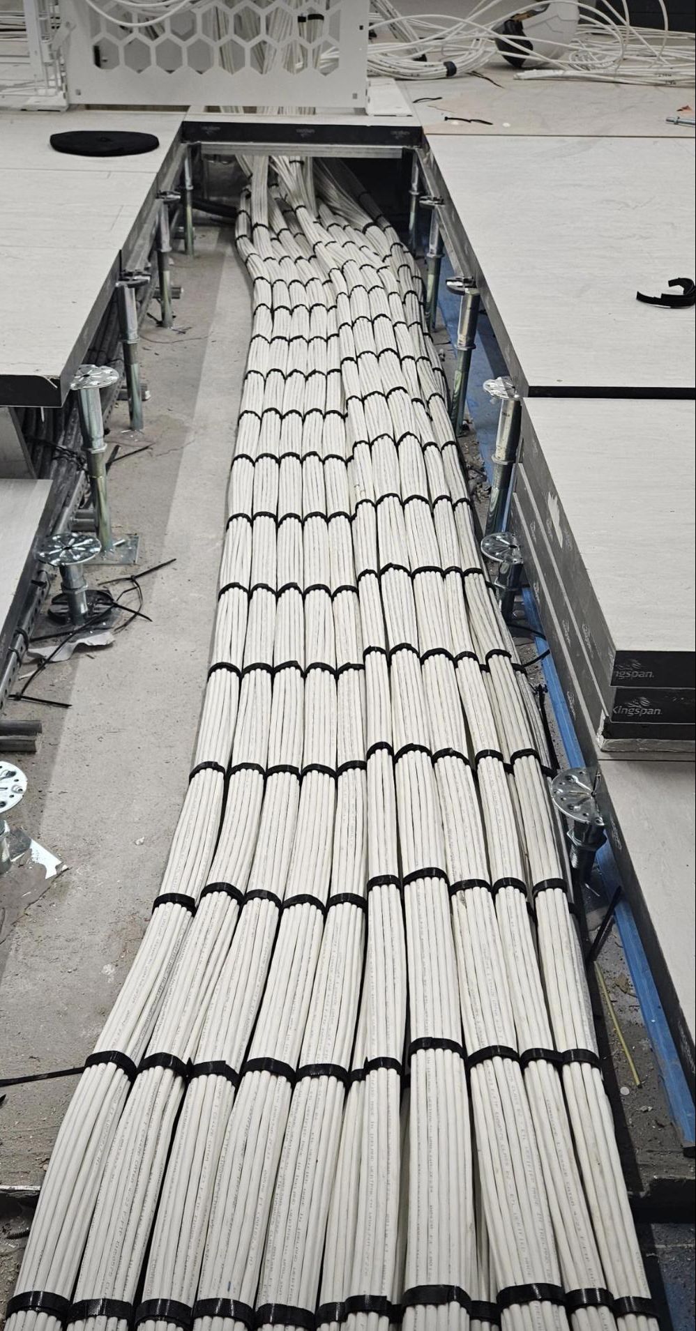 Bundled white copper cables under a raised floor